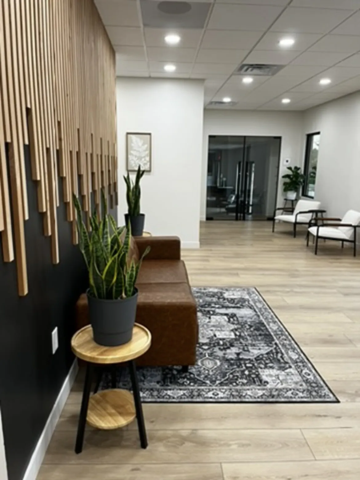The reception and waiting area with a timber slat wall, leather seating and plants.