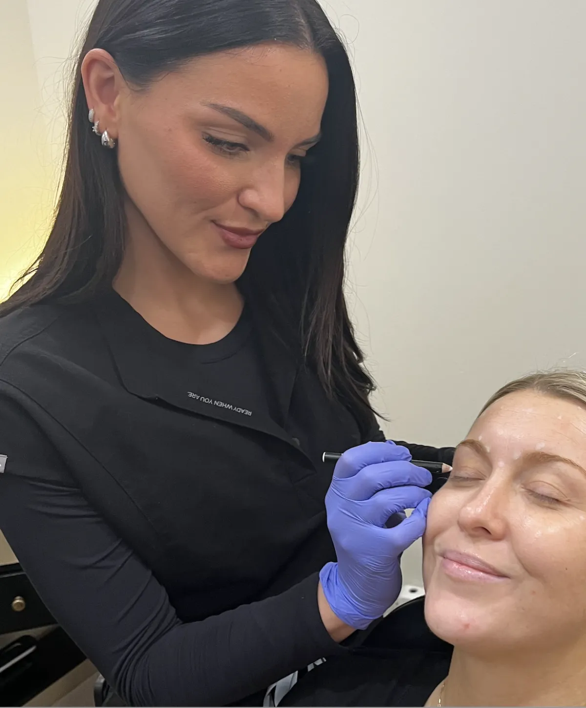 A gloved provider treating a patient's upper face during an appointment at Alchemy.